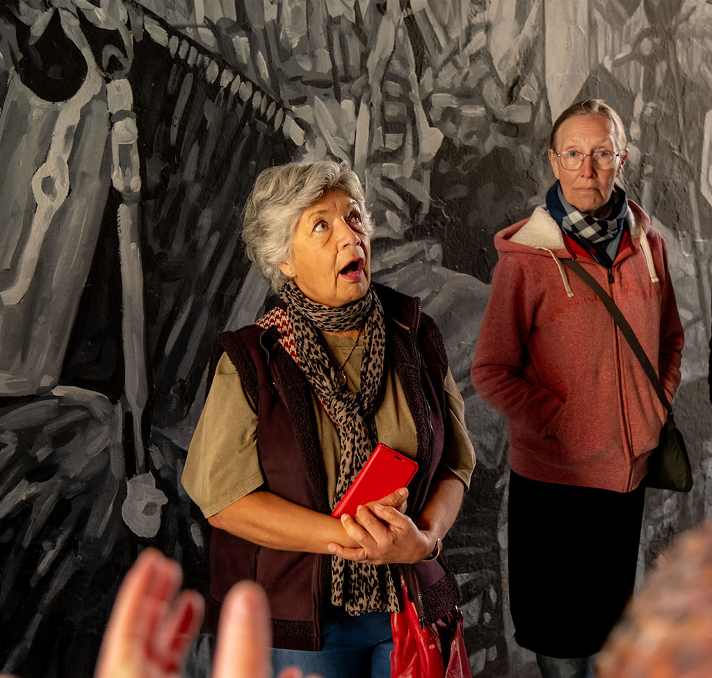 Tour member looking surprised in dark alleyway in front of mural